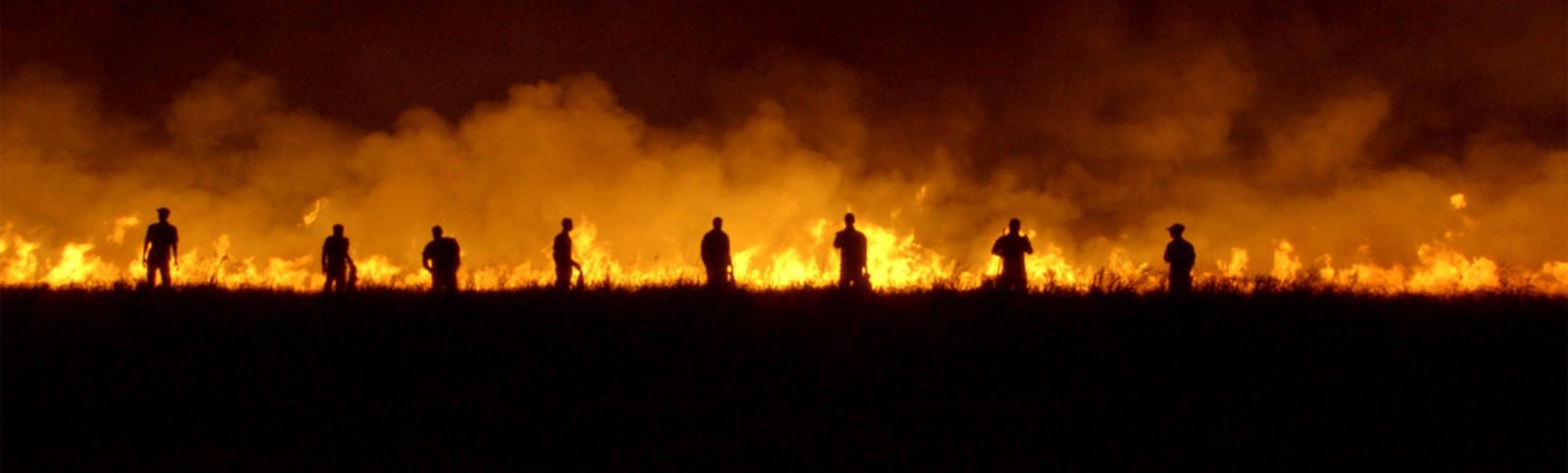 Silhouettes of people walking near field on fire, from Rojek