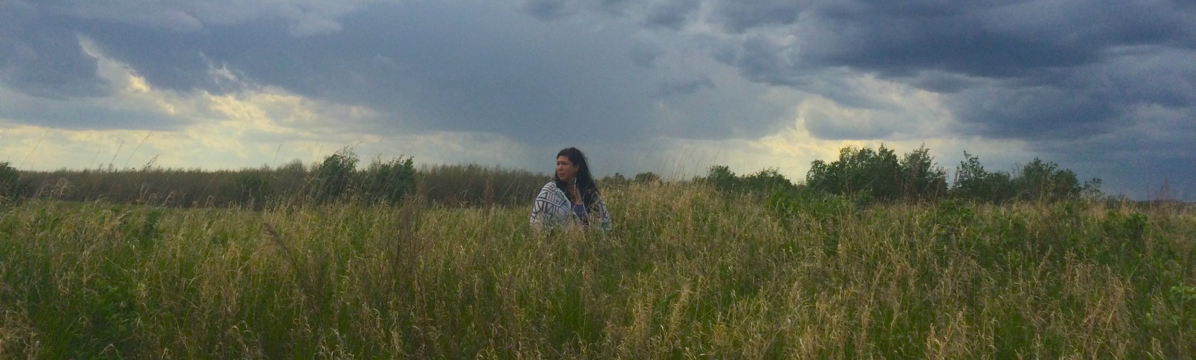 Tasha Hubbard standing in a field, from Nipowistamasowin