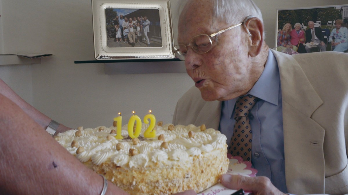 Man blowing out 102 candle on cake