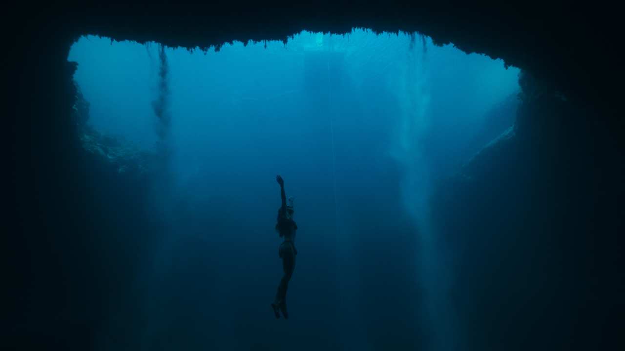 a young woman swimming underwater and heading to the surface