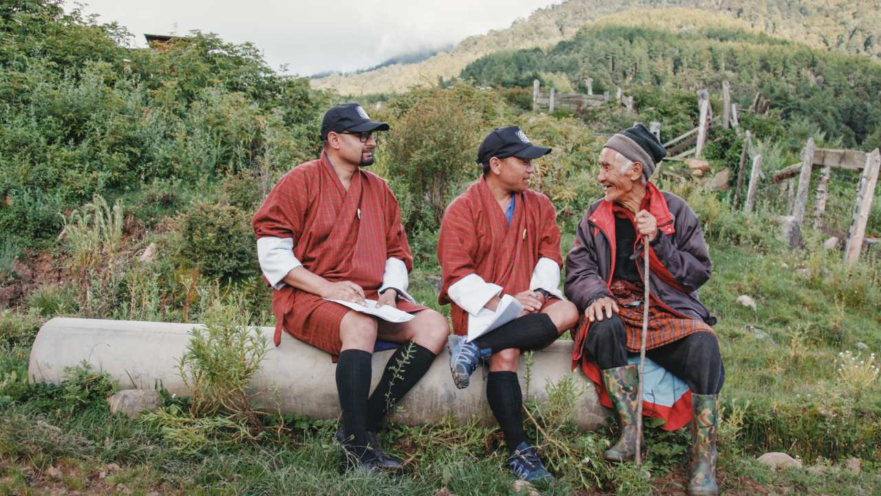 three men sitting together on a log