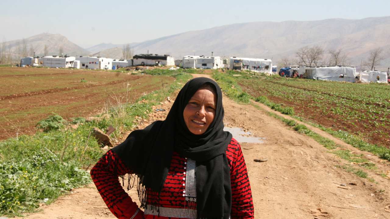 a woman standing in a field looking at the camera