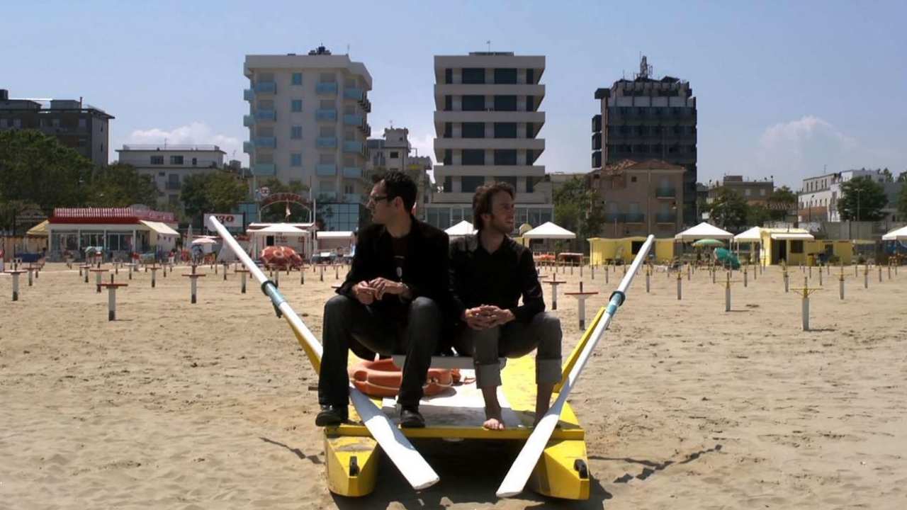 two men sitting at a beach