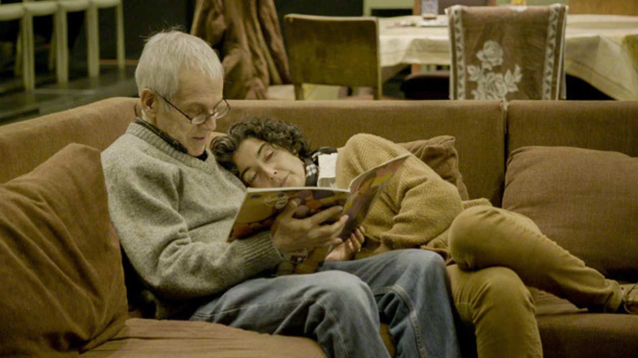 a couple embraced on a couch while reading together