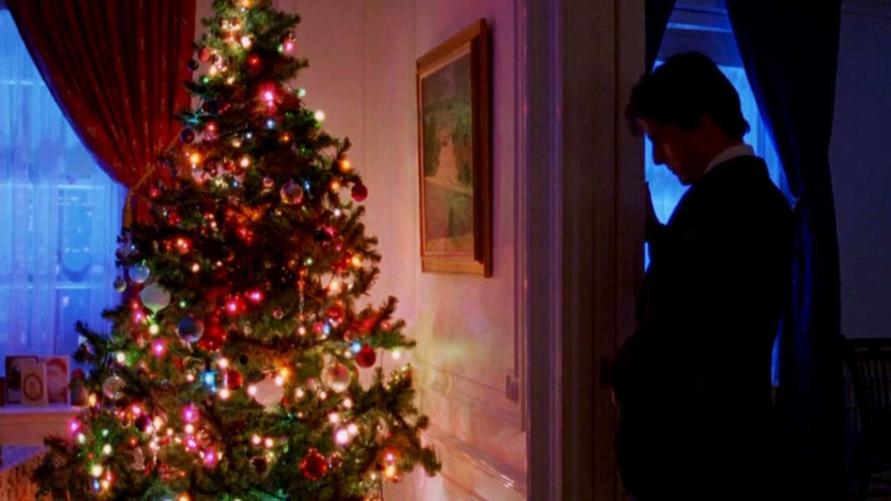 a man standing in the shadows next to a Christmas tree