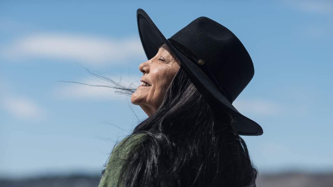 side profile of a woman in a wide brim hat smiling