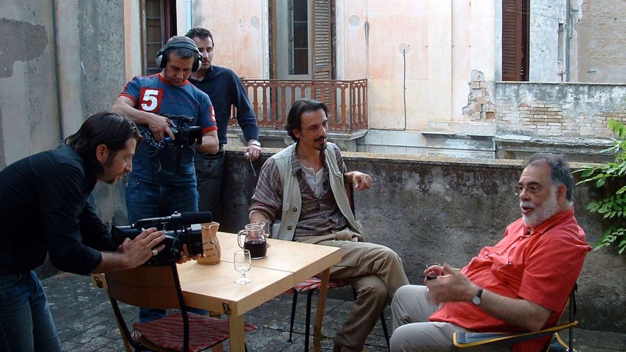 three men filming two men talking over drinks