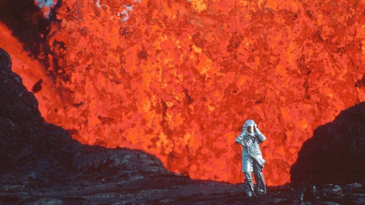 person in a fire proof suit in front of a volcano