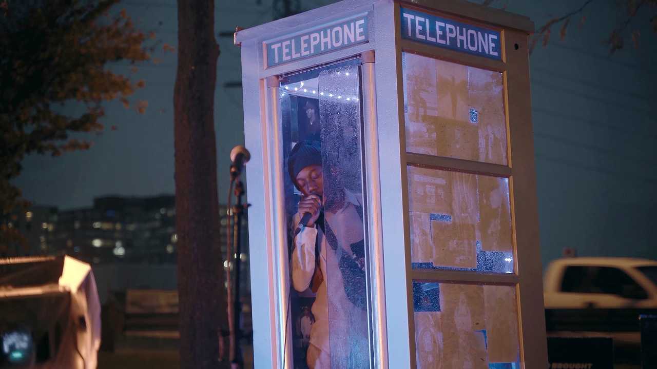 a man singing in a phone booth