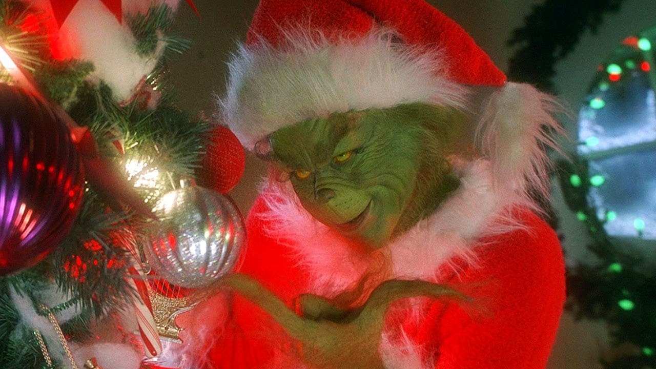 the Grinch dressed as Santa and looking at Christmas decorations