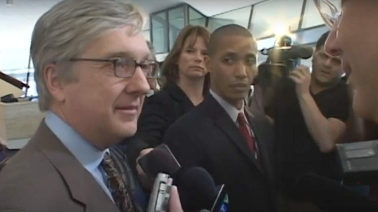 two men in suits and reporters