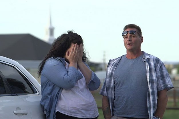 Woman crying with man beside car