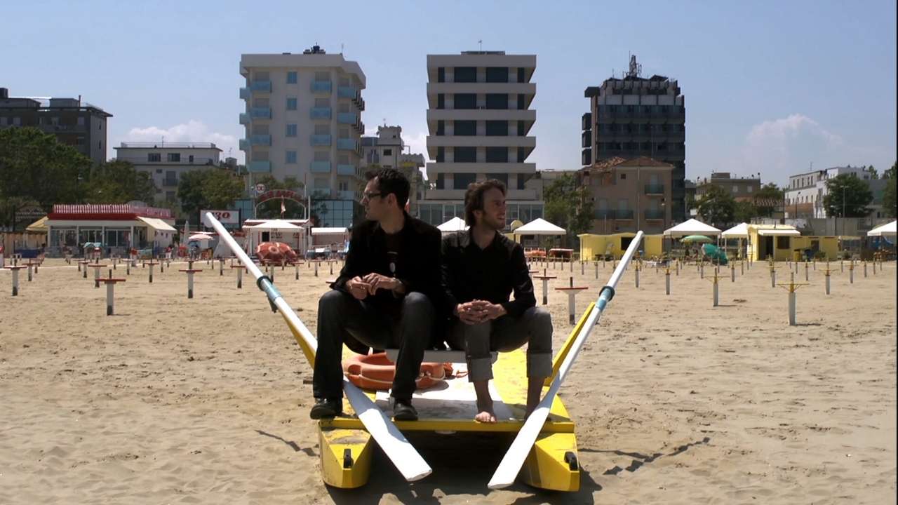 two men sitting on a beach