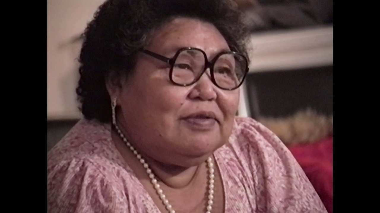 a woman with glasses and a pearl necklace
