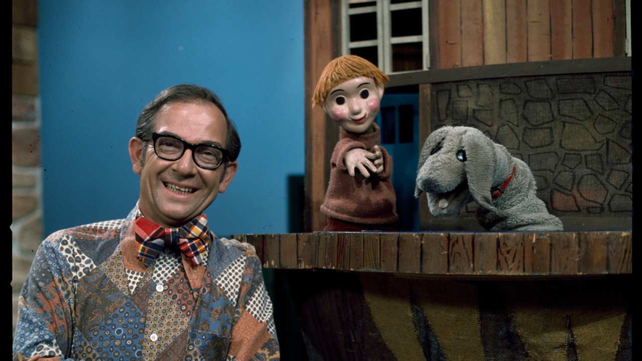 a man with glasses and two puppets