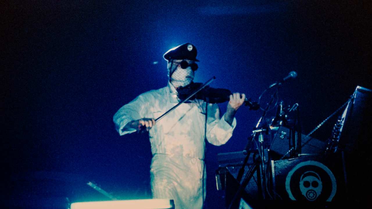 a man wrapped in bandages with sunglasses and a hat playing the violin