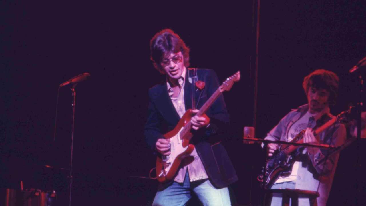 a man in a blazer playing the guitar
