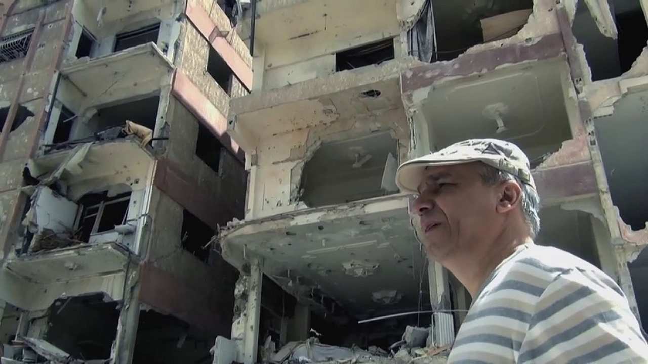 a man in a striped shirt walking by half demolished buildings