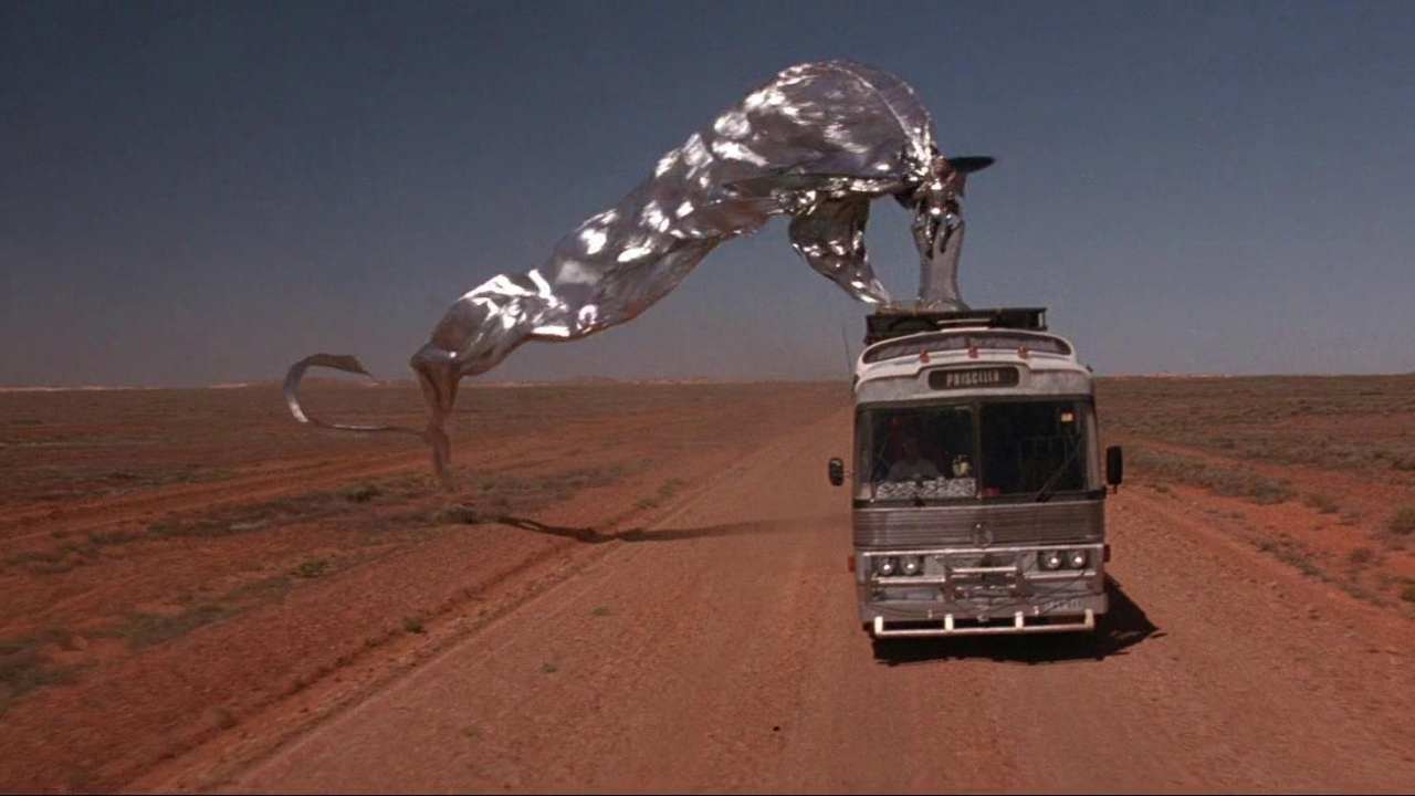 a drag queen in silver on top of a bus