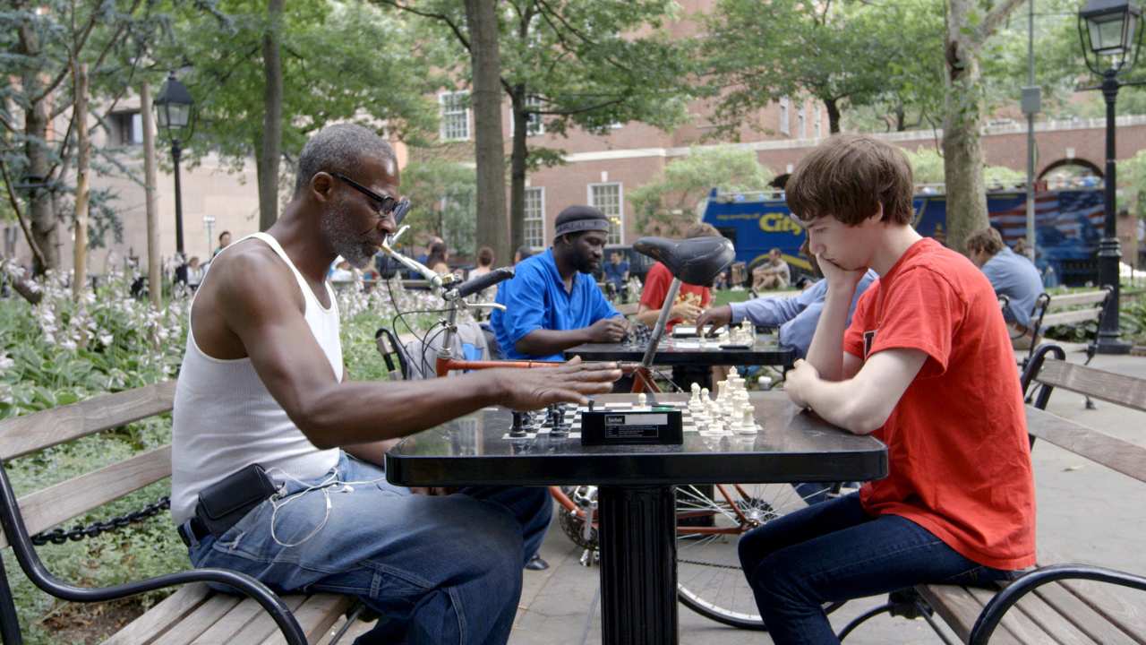 a man and a boy playing chess in a park