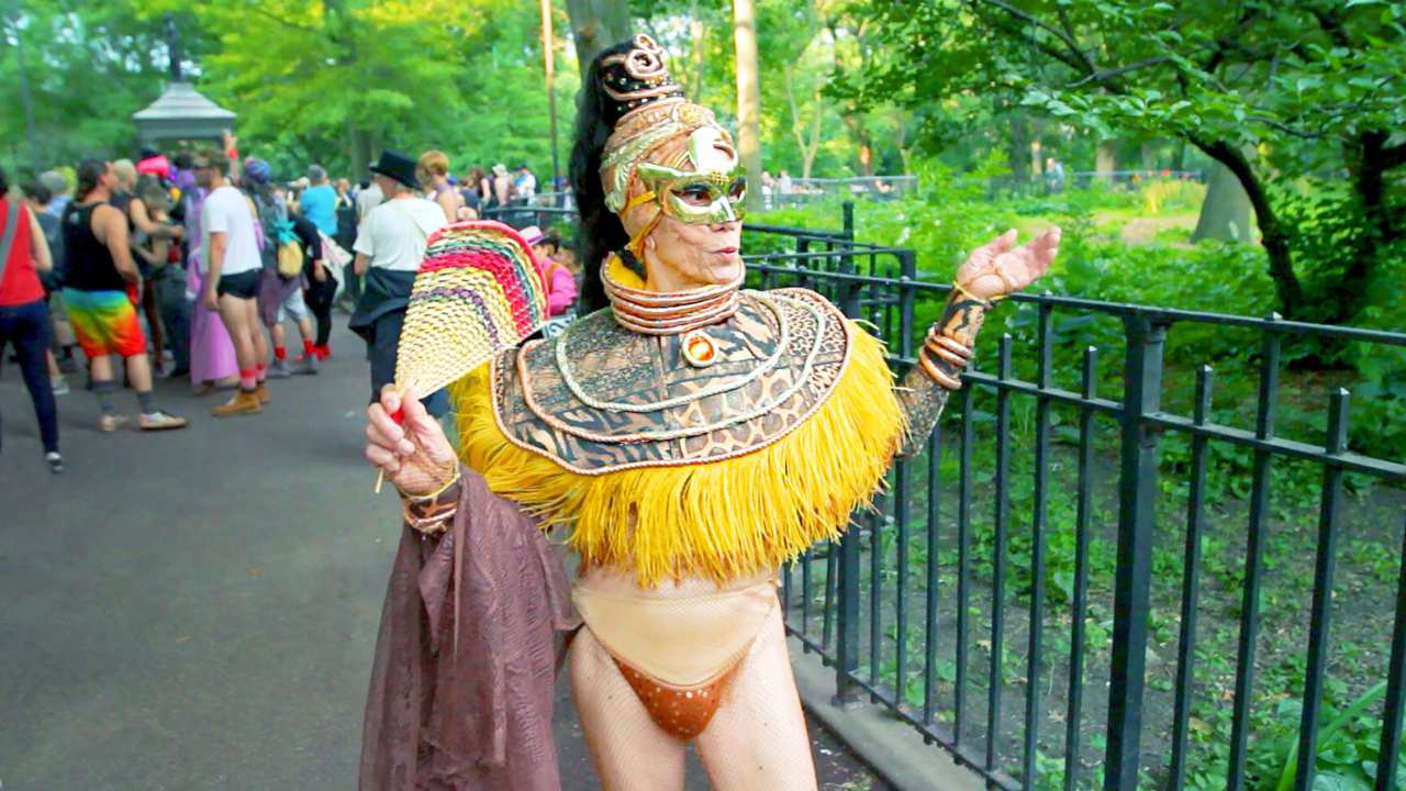 a drag queen in a mask and a capelet