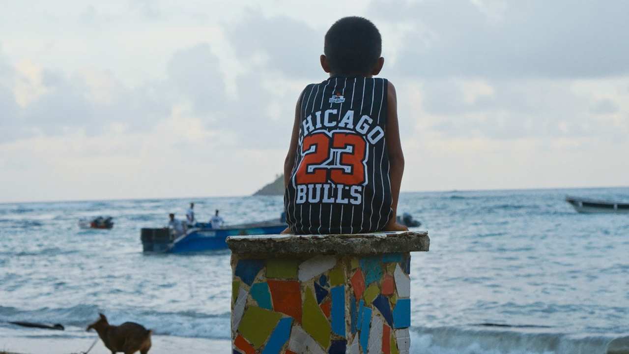 a boy in a Bulls jersey sitting looking at the ocean