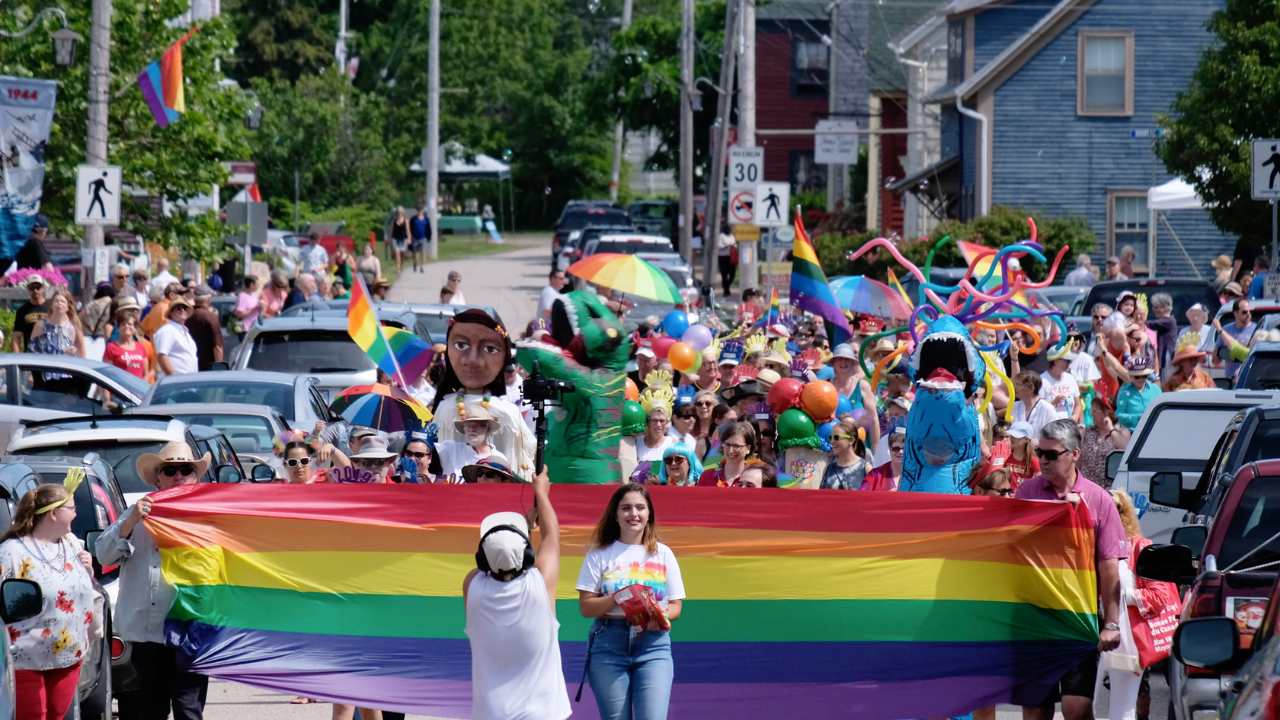 a Pride parade full of smiling people with rainbow flags