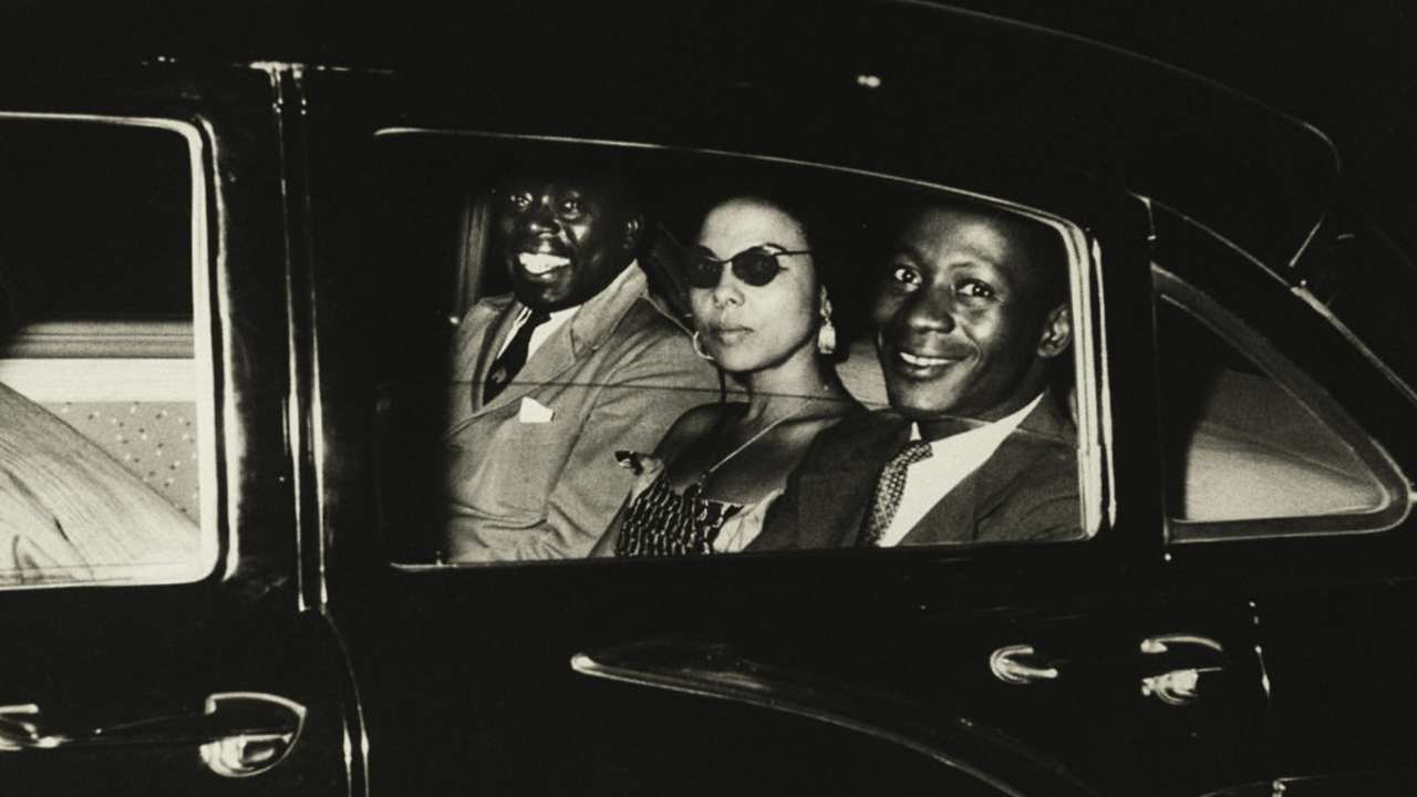 two men and a woman sitting in the back of a car