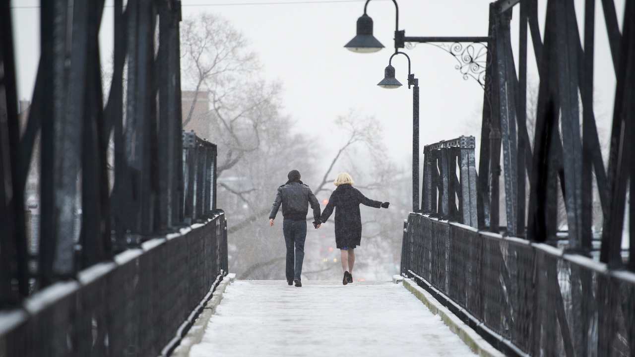 two people holding hands and walking across a bridge