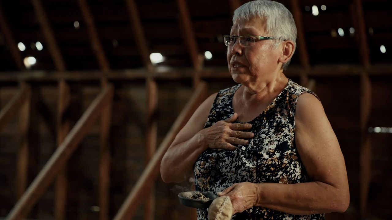 a woman with glasses facing the left and speaking