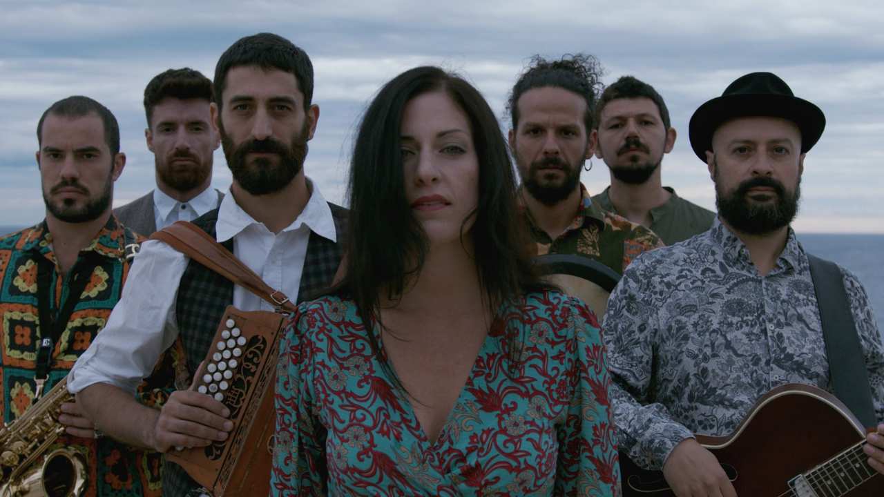 a woman standing with a group of men with musical instruments