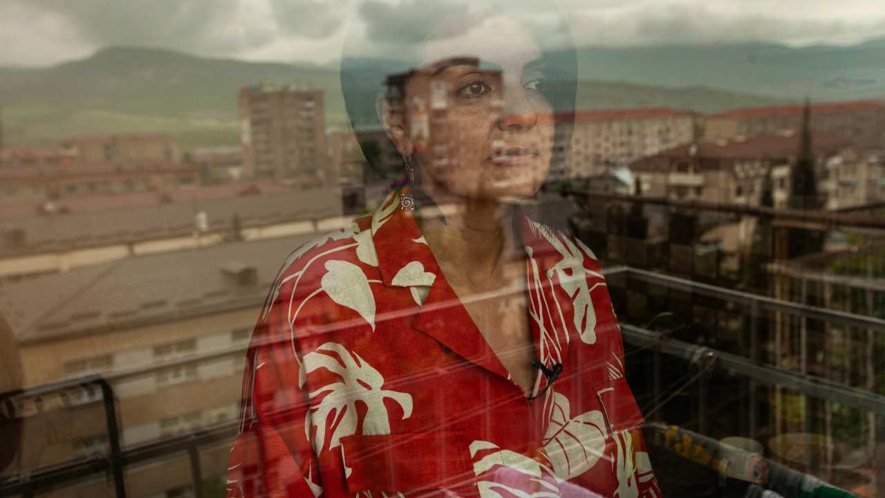a woman looking through a window in a red floral top