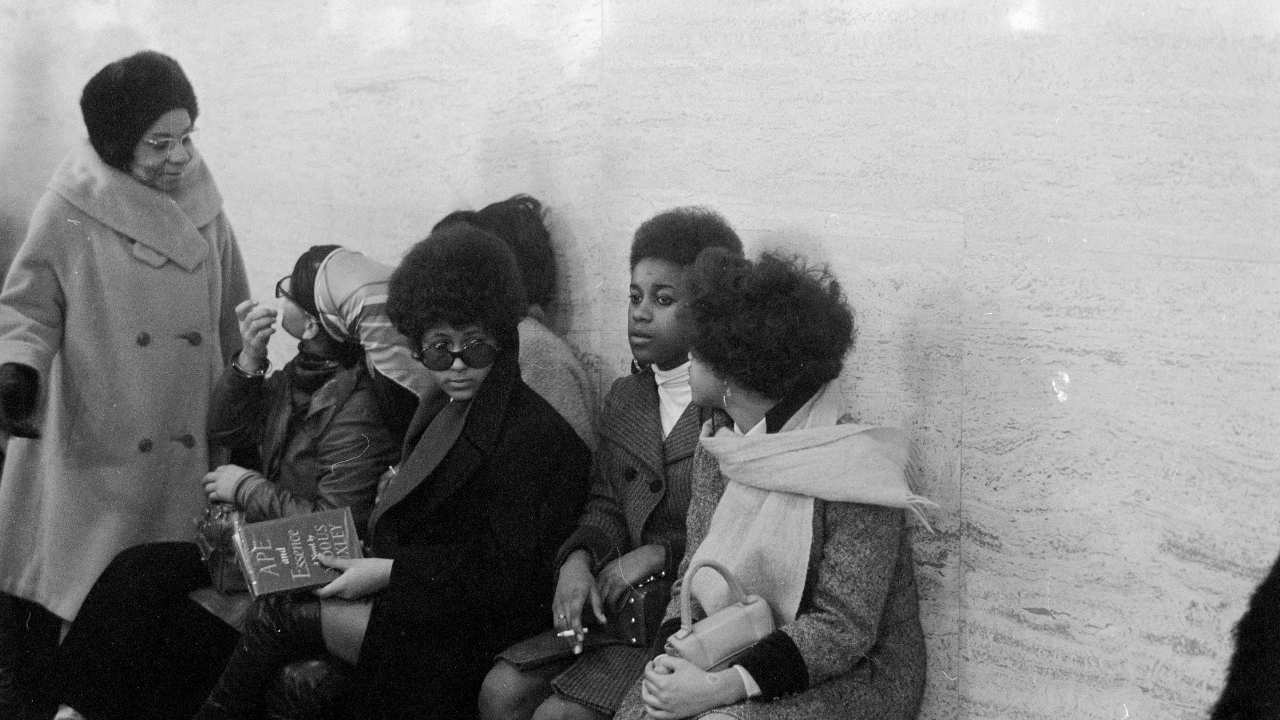 a group of women in coats and scarves sitting together